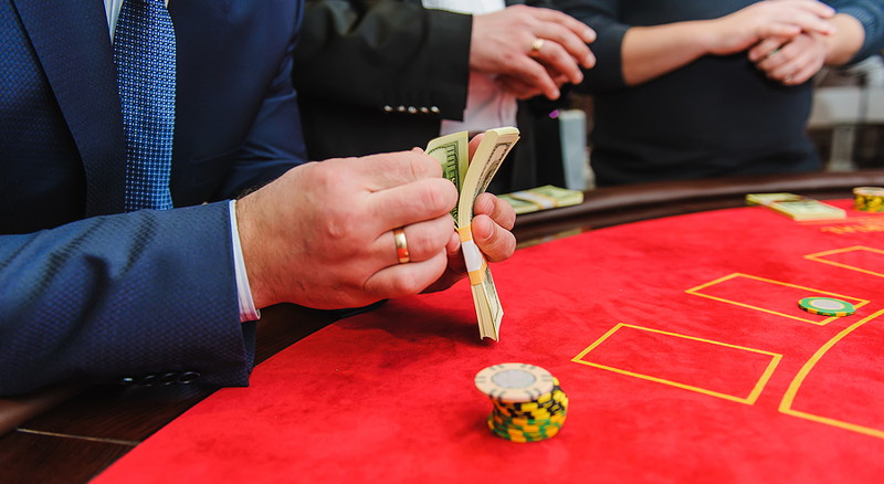 man with bundles of cash at blackjack table