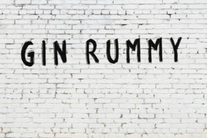 gin rummy word written in black on white brick wall